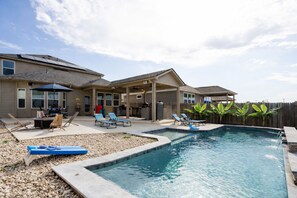 Un jardin avec une piscine, des chaises longues et un espace barbecue.