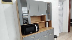 A kitchenette with grey cabinets, a microwave, and a small countertop. - Brisa e Mar Townhouse (Caraguatatuba)