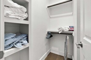 A small, neatly organized bathroom with a towel rack, shelves with folded towels, and a shower area. - Modern East Austin Home – Walk to Downtown! (Austin)