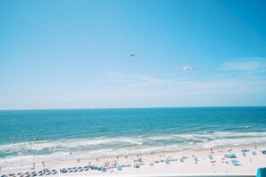A beach with people, umbrellas, and a plane in the sky. - 3BR Gulf View Condo, Balcony, Beach Access (Orange Beach)