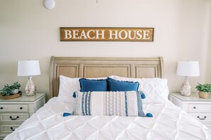 Een slaapkamer met een bed, twee nachtkastjes, een bord aan de muur en een nachtkastje met een lamp.
