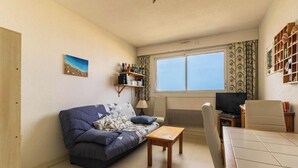 Ett vardagsrum med en soffa, ett soffbord, en tv och en bokhylla.