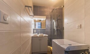 Une salle de bain équipée d’une douche, d’un lavabo, d’un miroir et de toilettes.