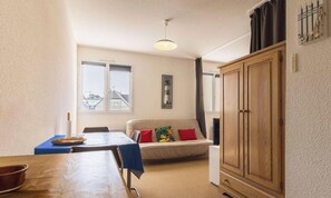 A room with a dining table, sofa, and wardrobe. - 2-person apartment near the beach in Sables-d’Or-les-Pins | Ref 115 (SABLES D OR LES PINS)
