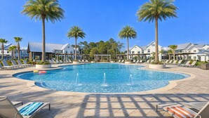 Ein Poolbereich mit einem runden Pool, Liegestühlen, Palmen und einem Gebäude mit heller Fassade im Hintergrund.
