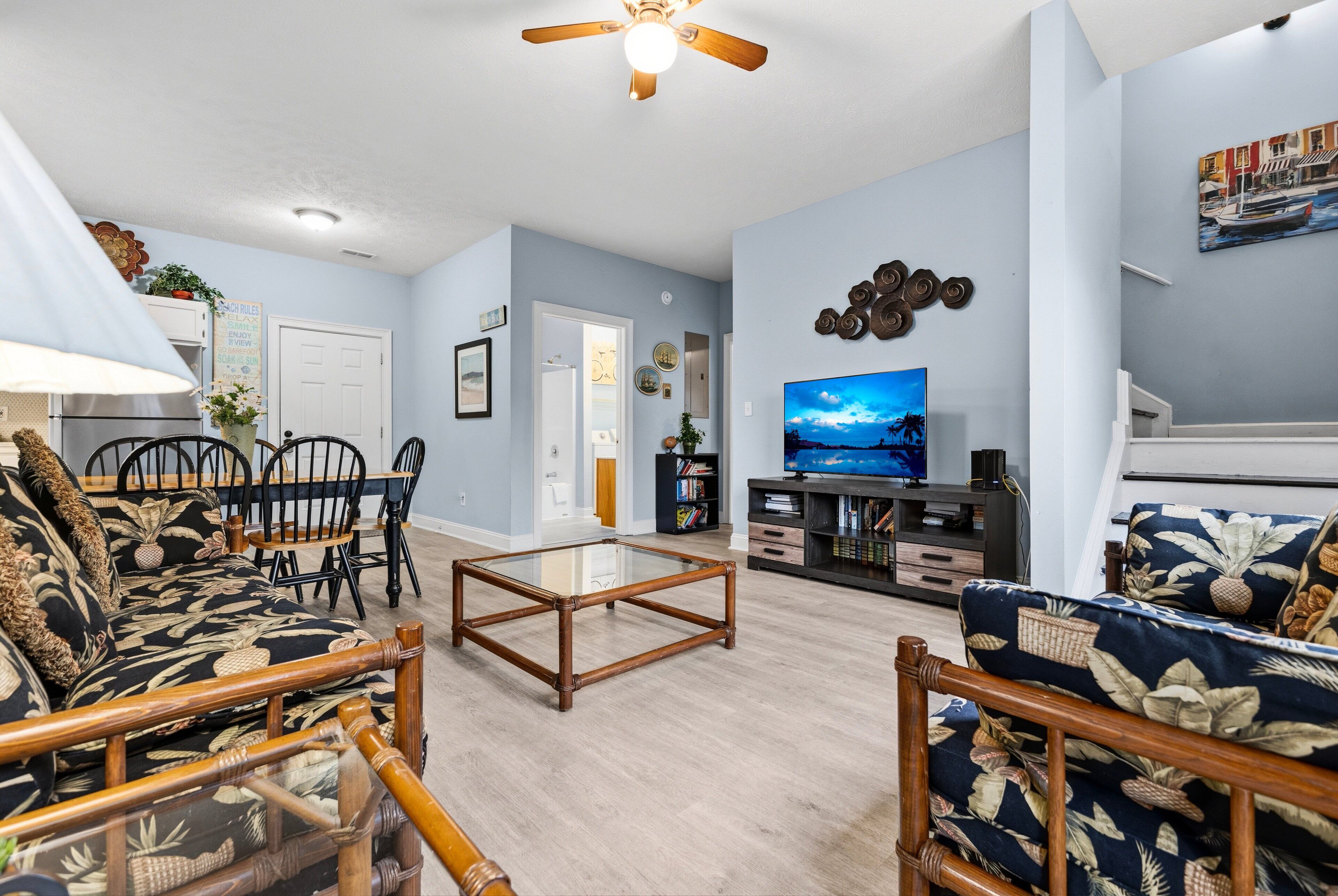 A living room with a sofa, chairs, a coffee table, a TV, and a ceiling fan.