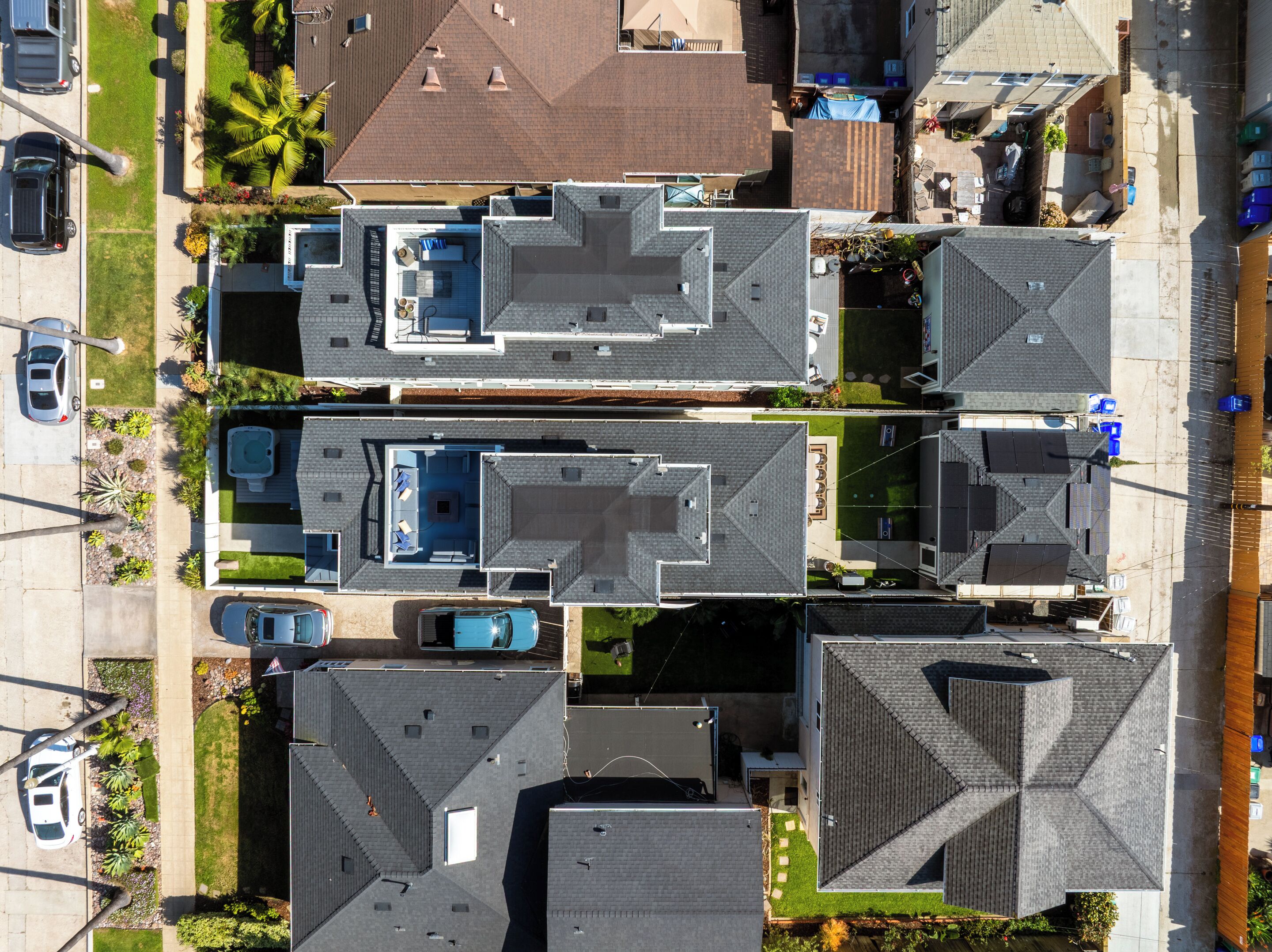 Un quartier résidentiel composé de plusieurs maisons, chacune ayant un style de toit distinctif et une piscine visible.