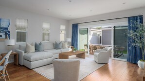 Een moderne woonkamer met een bank, fauteuils, een salontafel en een eethoek met stoelen.