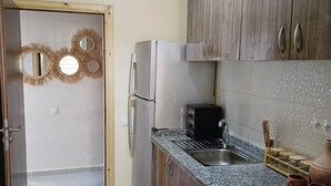 Une cuisine avec des meubles en bois, un réfrigérateur en acier inoxydable, un plan de travail en granit et un évier.