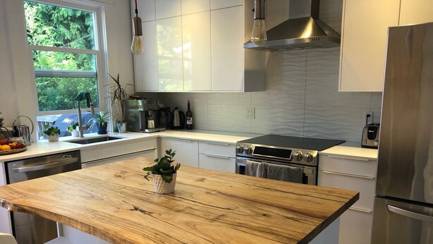 Una cocina moderna con una isla de madera, electrodomésticos de acero inoxidable y vistas al exterior.