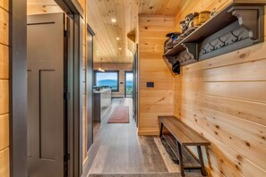 Ein Holzflur mit einer Bank, einem Schuhregal und Blick ins Freie.