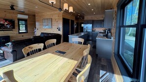 Een moderne keuken met houten kastjes, een centraal eiland en een eethoek met een houten tafel en stoelen.