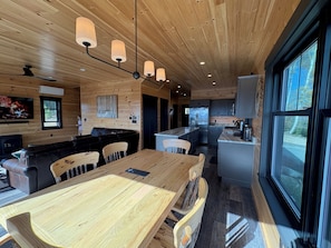 Eine moderne Küche mit Holzschränken, einer zentralen Kochinsel und einem Essbereich mit Holztisch und -stühlen.