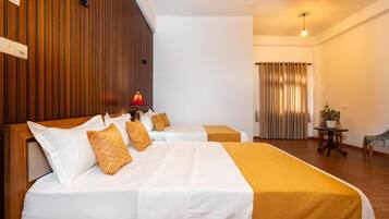 A hotel room with two beds, wooden paneling on one wall, a ceiling fan, and a window with curtains.