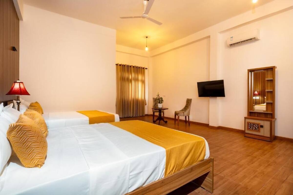 Une chambre d’hôtel avec deux lits, une télévision, une chaise, une petite table et un appareil de climatisation.