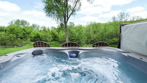 A hot tub with three chairs, surrounded by greenery.