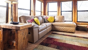 A wooden interior with a leather sofa, a lamp, and a rug.