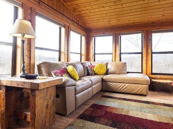 Un intérieur en bois avec un canapé en cuir, une lampe et un tapis.