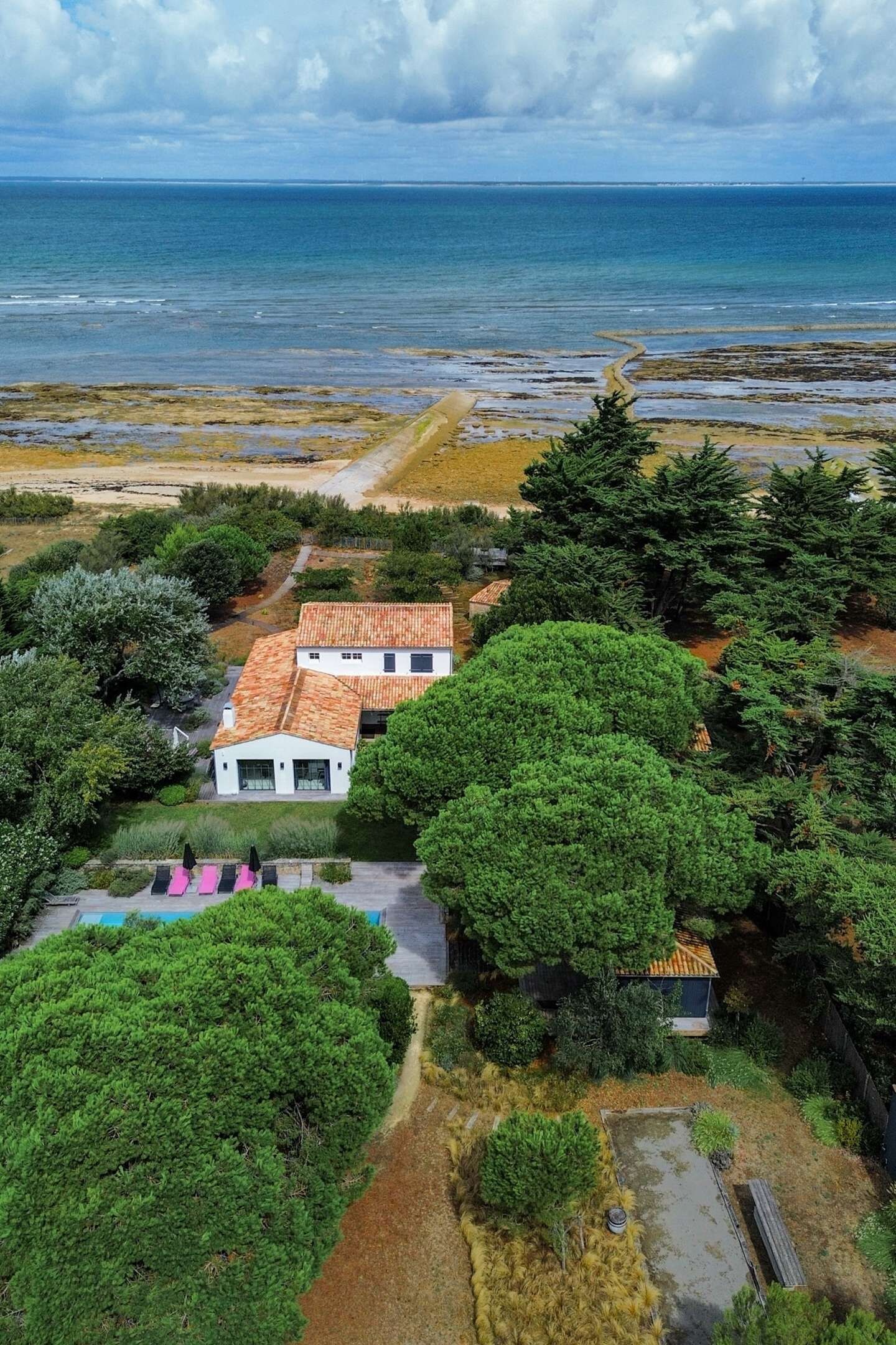 Une propriété située sur la côte, avec un bâtiment blanc, une piscine et une vue sur la mer.