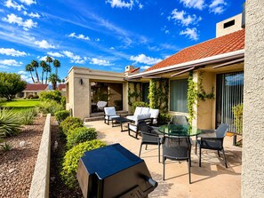 A patio with outdoor furniture, a barbecue grill, and a view of a residential area with palm trees. - Grande Vista Villa: 3 bed/3 bath Luxury Living; Stunning Lake & Mountain Views | a Greenday property (Rancho Mirage)