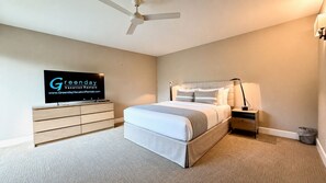 Ein Schlafzimmer mit Bett, Fernseher, Nachttisch, Lampe und Deckenventilator.