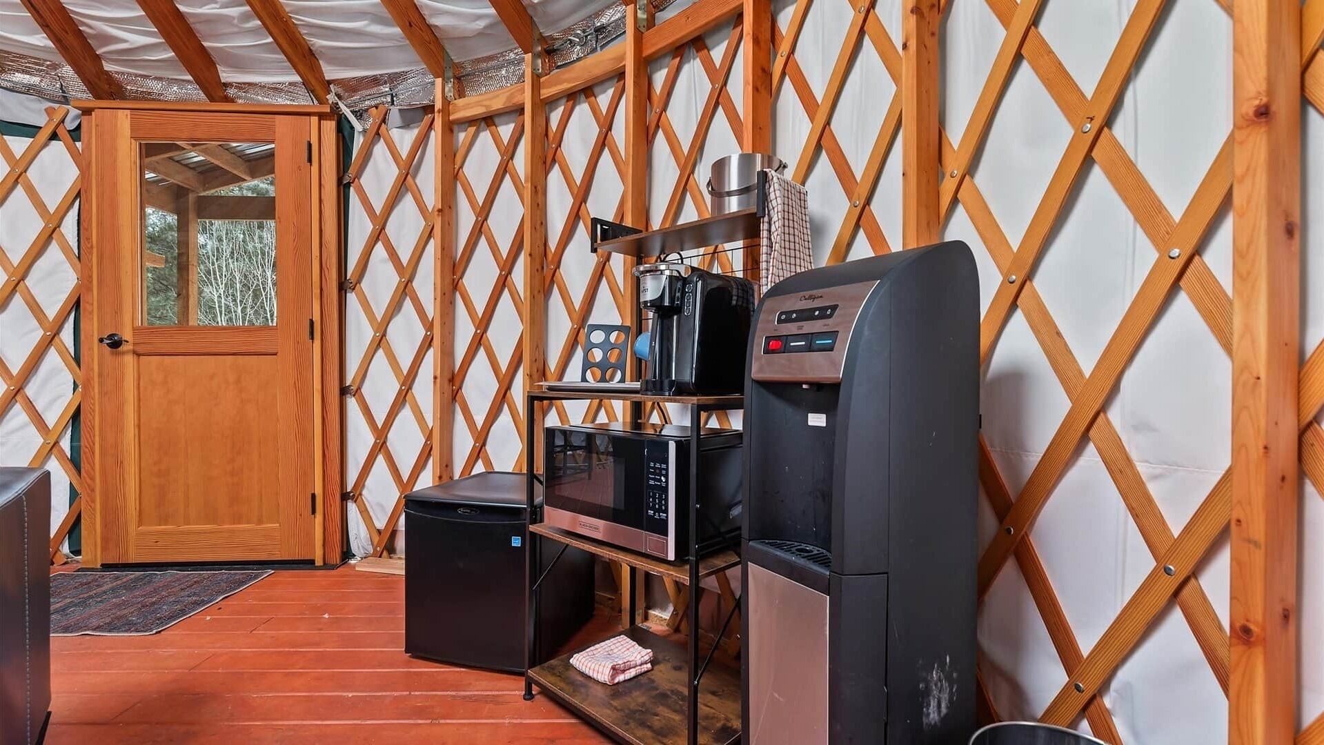 Un espace cuisine compact comprenant un réfrigérateur, un four à micro-ondes, une machine à café et un grille-pain.