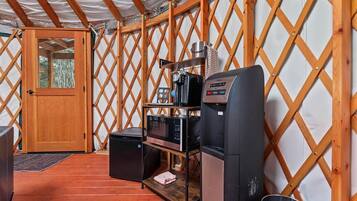 Un espace cuisine compact comprenant un réfrigérateur, un four à micro-ondes, une machine à café et un grille-pain.