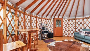A yurt with a wooden interior, a dining table, a sofa, and a cowhide rug. - Yurt 2 - The Gold Miner (Boise County)