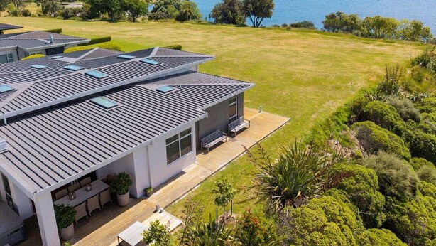 A modern house with a large patio area, a swimming pool, and a view of a lake. - Lakefront Kuiwai - lakefront with spa pool (Taupo)