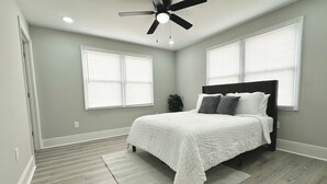 A bedroom with a bed, a ceiling fan, and two windows with blinds. - Cozy 2-bedroom cottage (New Orleans)