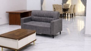 Ein modernes Wohnzimmer mit einem grauen Sofa, einem Holztisch und einem Essbereich mit Stühlen und einem Tisch.