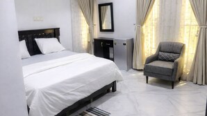 Ein Hotelzimmer mit Bett, Sessel, Schreibtisch und Spiegel.