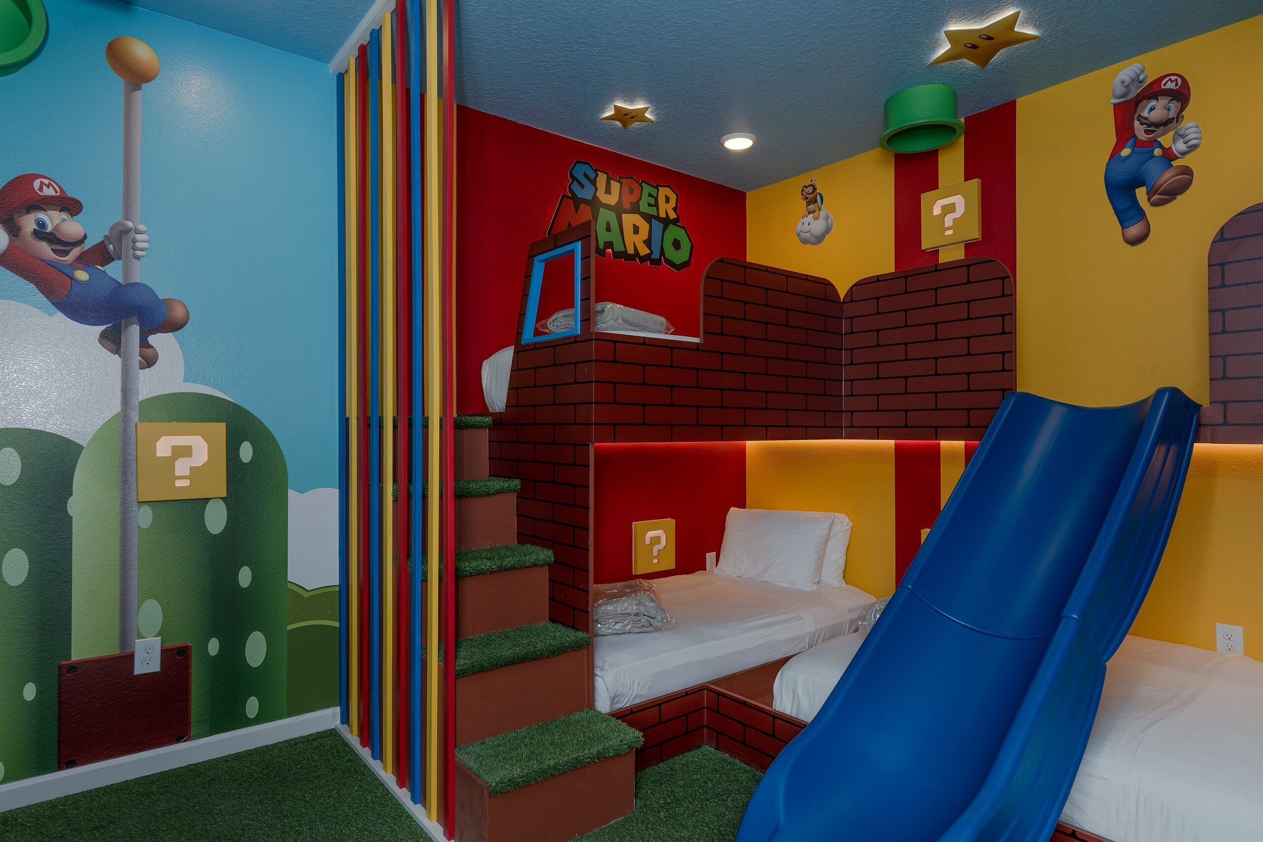 A children's room with a Mario-themed mural, bunk beds, a slide, and a play area with a question mark sign.