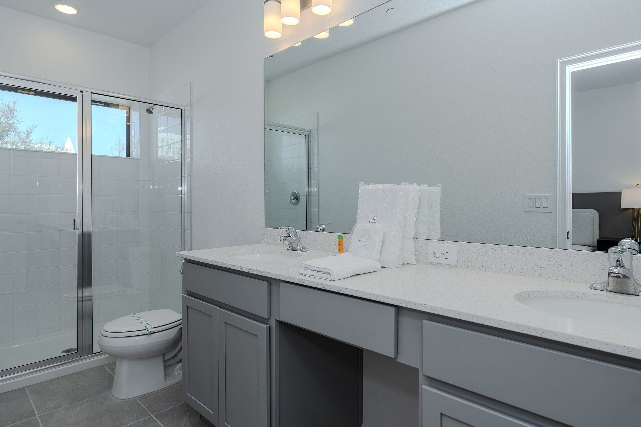 Une salle de bain moderne avec une douche à parois de verre, des toilettes, un lavabo avec un miroir et un porte-serviettes.