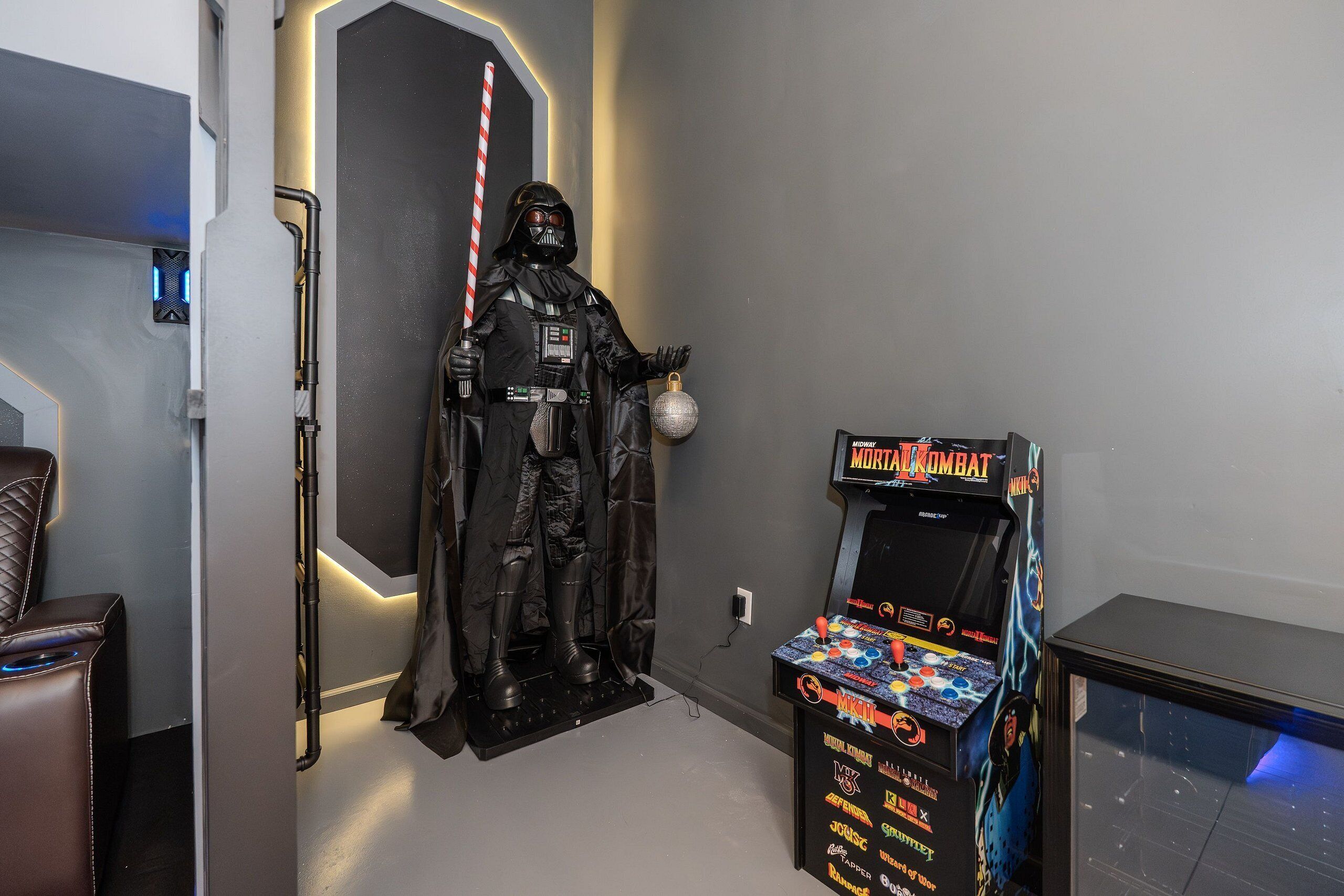 A room with a Darth Vader statue, a Mortal Kombat arcade machine, and a gaming chair.