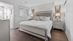 A bedroom with a large bed, two bedside tables, a dresser, and a mirror. - 2BR 2.5BA Marsh views Amenity Access (Seabrook Island)
