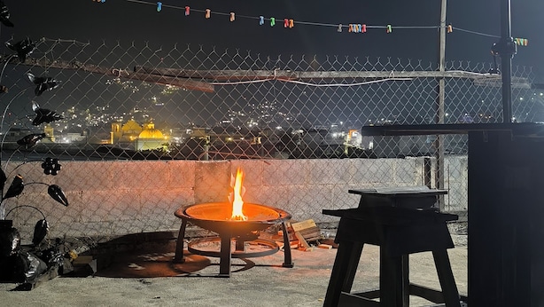 A patio area with a fire pit, outdoor furniture, and a view of a stadium at night. - Karim Hostal Antigua (Guatemala City)