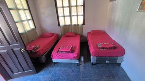 A room with three single beds, each with a red bedspread and pillows. There is a window with curtains, a door, and a small painting on the wall. - Karim Hostal Antigua (Guatemala City)