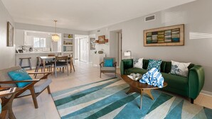 A modern living room with a green sofa, striped rug, and wooden coffee table. - Some Like It Hot at Runaway Bay 148 (Bradenton Beach)