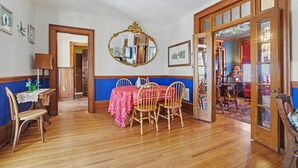 Un coin repas avec une table et des chaises en bois, un miroir et une nappe rouge.