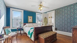 Quarto com cama, penteadeira, cadeira e ventoinha no teto.