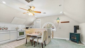 Una cocina con armarios blancos, una estufa y un comedor con mesa y sillas.