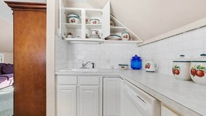 Una cocina con armarios blancos, un pilar de madera y un contenedor azul.