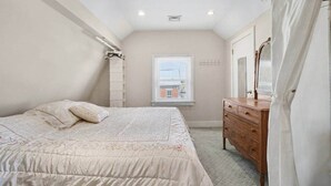 Un dormitorio con cama, cómoda y ventana con persianas.