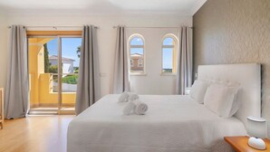 Una camera d'hotel con un letto grande, un balcone con tende e vista su un edificio.