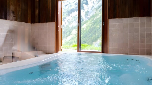 Un jacuzzi con vista a un paisaje montañoso a través de un ventanal.