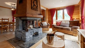Un interior acogedor de cabaña con chimenea de piedra, muebles de madera y ventanas amplias.
