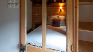 Un interior de madera con una cama, un enchufe y una lámpara.