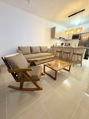 A modern living room with a sofa, a wooden rocking chair, and a coffee table.