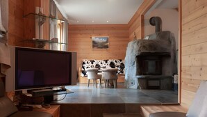 A modern interior with a TV, dining area, and stone fireplace. - Chalet “Eden” with Balcony and Wi-Fi (Les Belleville)